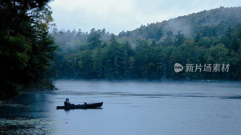人独木舟钓鱼在雨，雾，鹤池，阿迪朗达克山脉，纽约