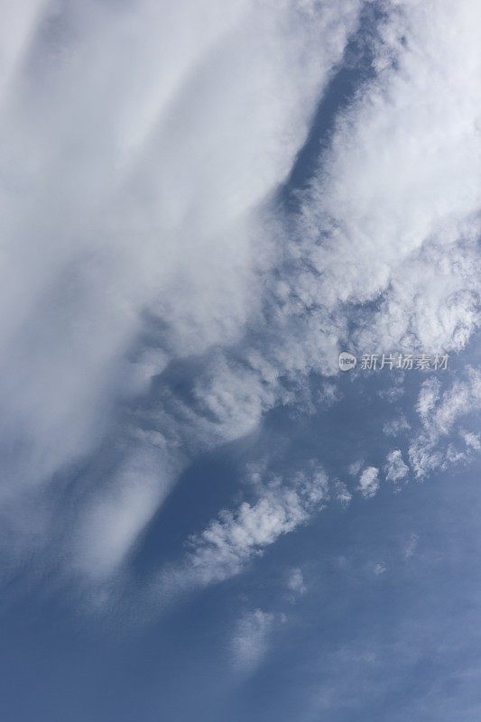 蓝色天空映衬着蓬松、缕缕白云的特写