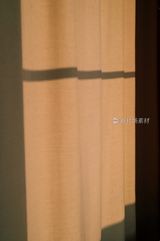日落时强烈的阴影落在窗帘上。米色的现代简约设计