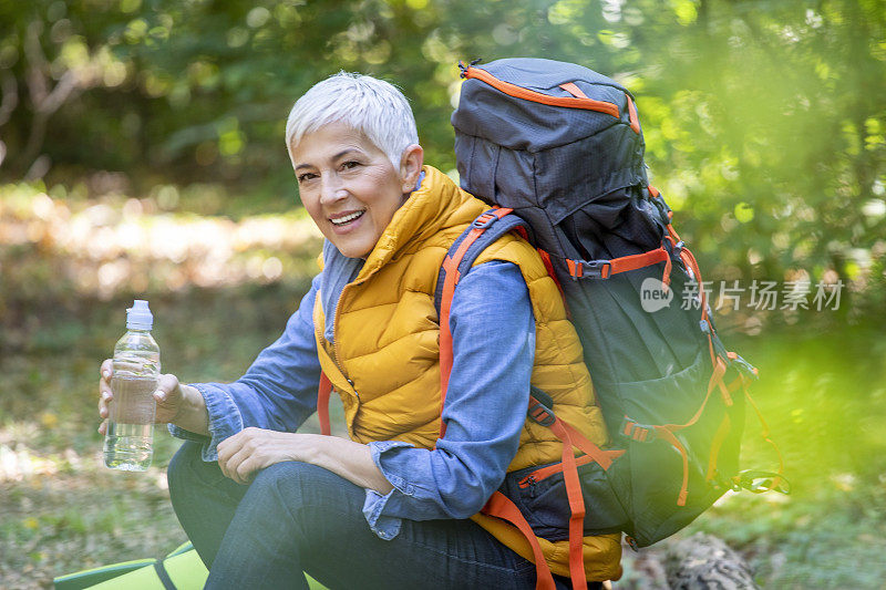 美丽成熟的老年妇女在60岁初的春天森林徒步旅行