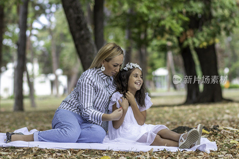 一个秋天的一天，年轻的妈妈和她可爱的女儿正在公园里享受