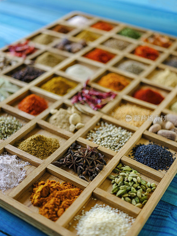 许多彩色的，有机的，干燥的，充满活力的印度食物香料在一个古老的绿松石色的背景木托盘，与大气的照明。