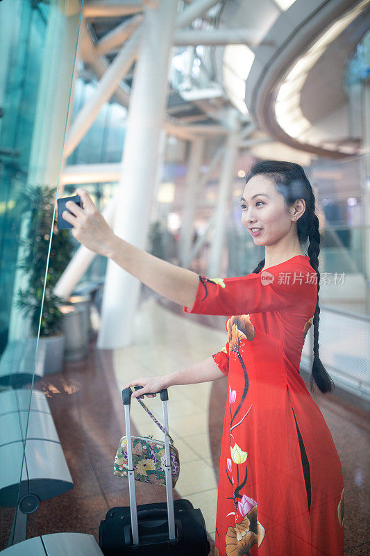 一名身穿红色奥戴的越南女子在机场自拍