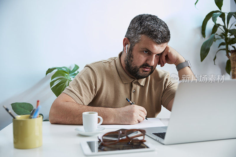 一个年轻人在他的家庭办公室里对着电脑说话