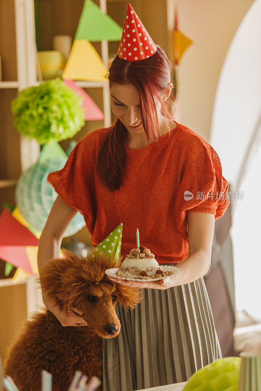 一个女人拥抱她的狗，他们在一起庆祝一个迷你生日