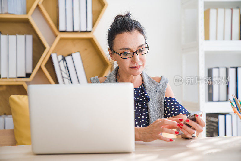 高级商务女性在度假时使用数码平板电脑和智能手机在家工作，在社交网络上玩网络游戏和发短信