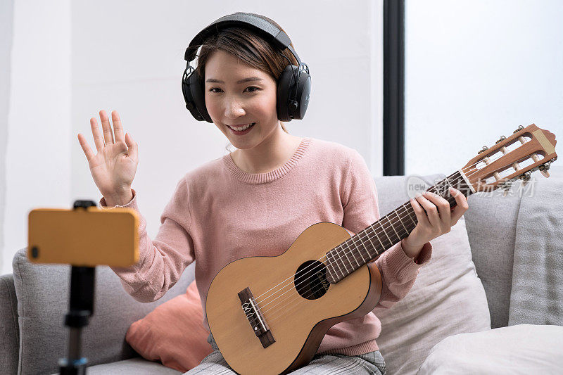 亚洲女性博客在社交媒体上直播弹吉他。