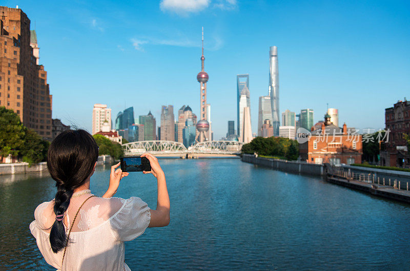 女游客在上海市中心拍照，从外滩散步欣赏天际线的景色