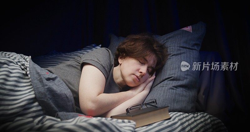 女人在床上看完纸书后正在睡觉