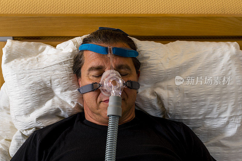 由于阻塞性睡眠呼吸暂停，男子戴着呼吸面罩睡觉