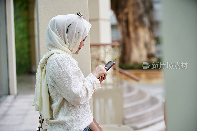 戴着头巾打电话的马来妇女