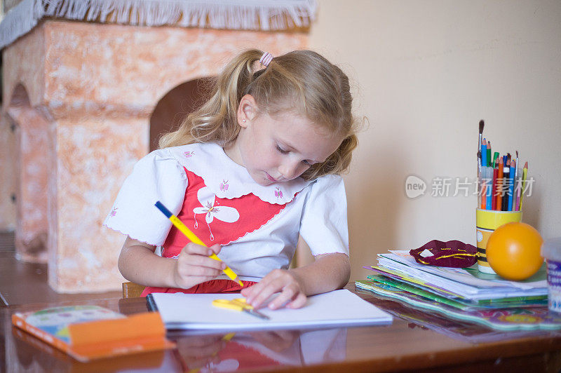 小女孩用铅笔在速写本上画画。