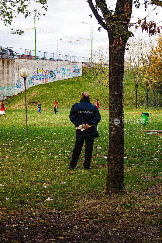 意大利交通管理员观察移民在公园里踢足球