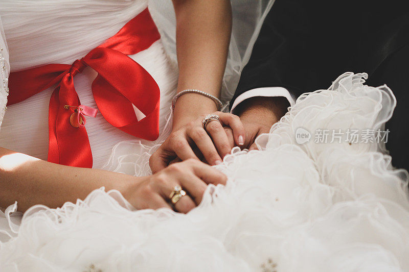 新娘和新郎手牵着手，特写。新娘的结婚戒指戴在手指上。
