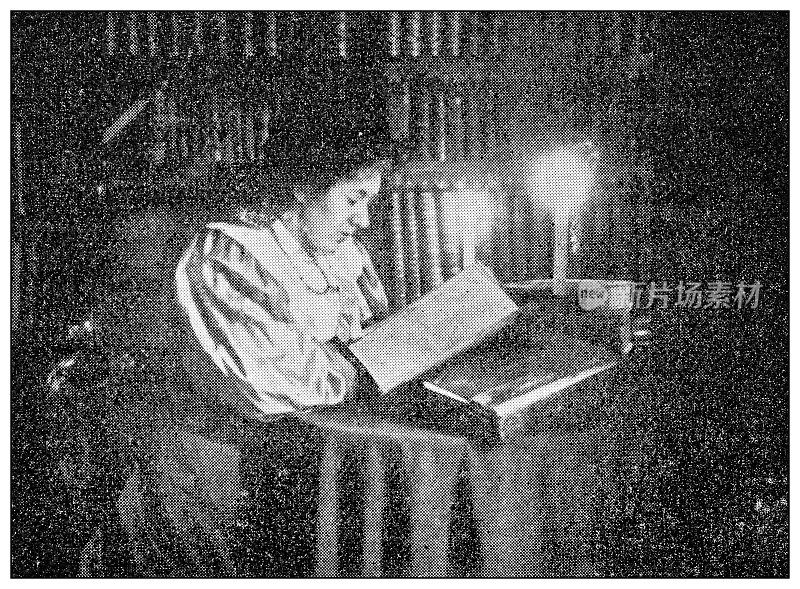 古董点印黑白照片:在烛光下阅读的女人
