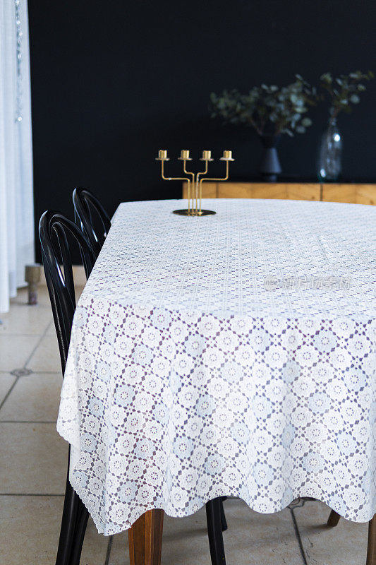 在家里的餐厅里有桌布、烛台和椅子的桌子
