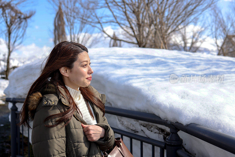 美丽的年轻女子在公园的积雪之间散步