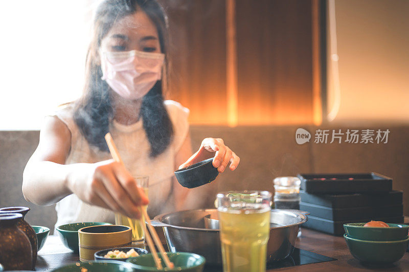 微笑的亚洲人戴着面具在亚洲等待享受日本涮锅自助餐