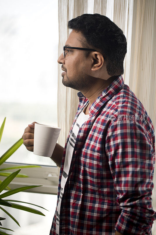 一个男人喝着咖啡，看着窗外
