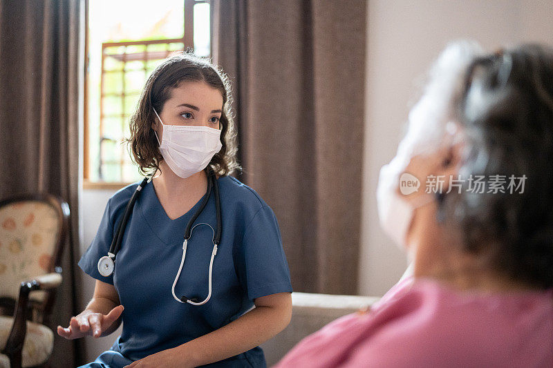 护士戴着口罩与家中的老年病人交谈