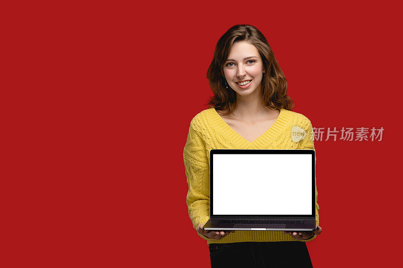 带复制空间模板的笔记本电脑。在工作室的女人与肖像电脑在红色背景。现代观念用的是空白宽屏显示器。人正在使用设备工作