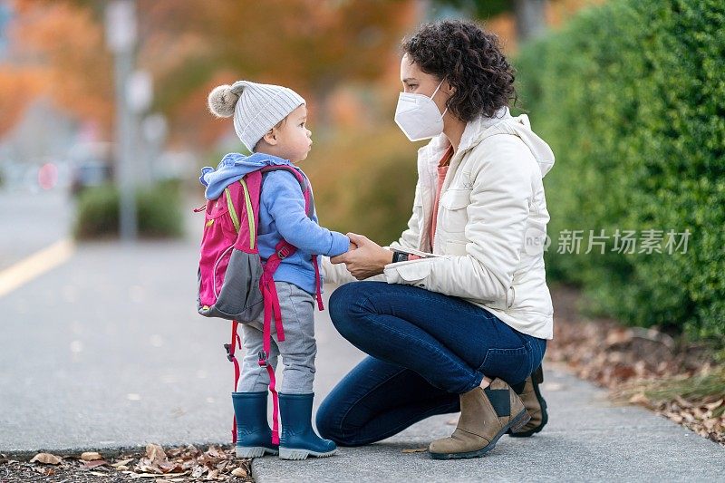 妈妈在学校和蹒跚学步的女儿说再见