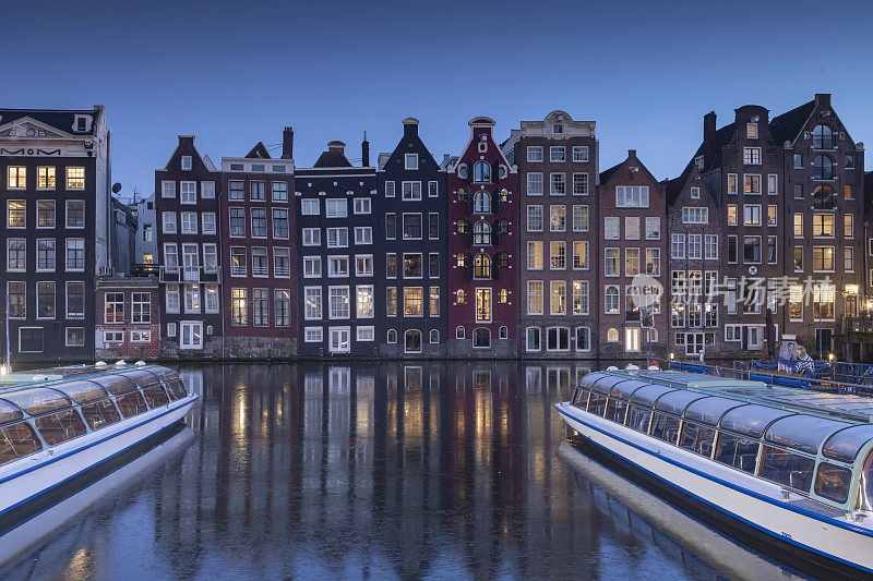 黄昏时分，阿姆斯特丹市中心Damrak上的观光船和运河房屋