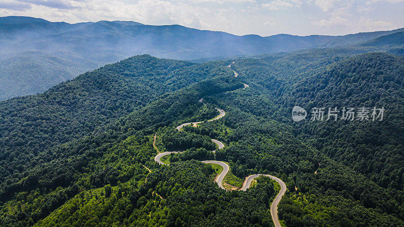 空中山地森林和道路，汽车通过道路，道路穿过树木，风景道路，夏季月空中道路视图，空中道路视图，道路旅行通过森林，背景摄影