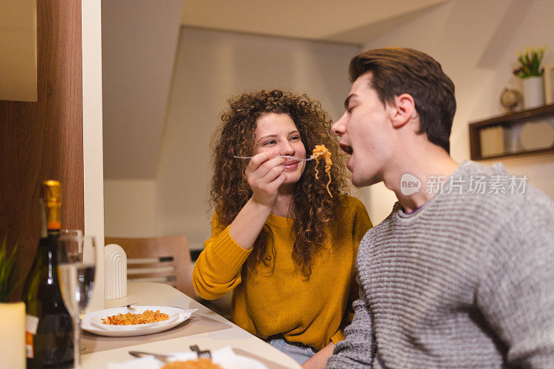 一对美丽的年轻夫妇在家里吃浪漫的晚餐，互相喂对方