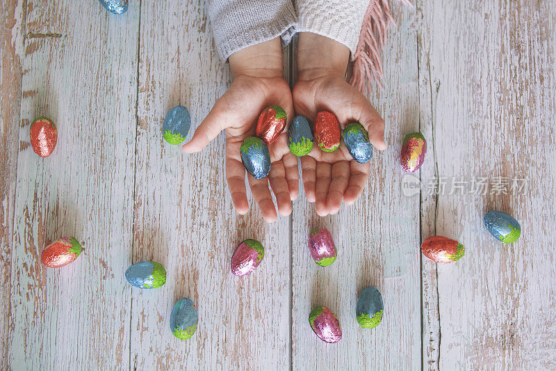 复活节。孩子们的手在木桌上拿着巧克力复活节彩蛋
