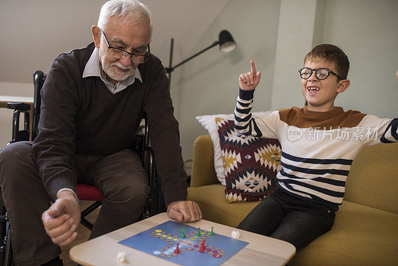 坐轮椅的老人和他的孙子在玩棋盘游戏
