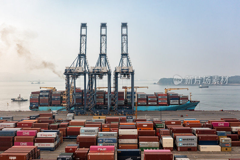 大雾天，大型货船在港口装卸集装箱