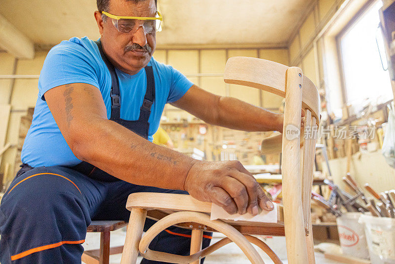 印度木匠独自在他的车间工作。他戴着安全眼镜