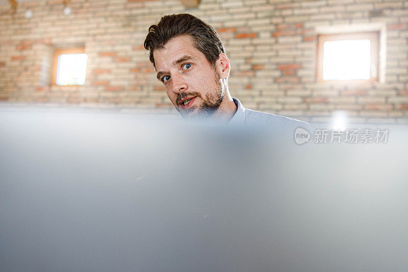 男性企业家在办公室用笔记本电脑进行视频通话。