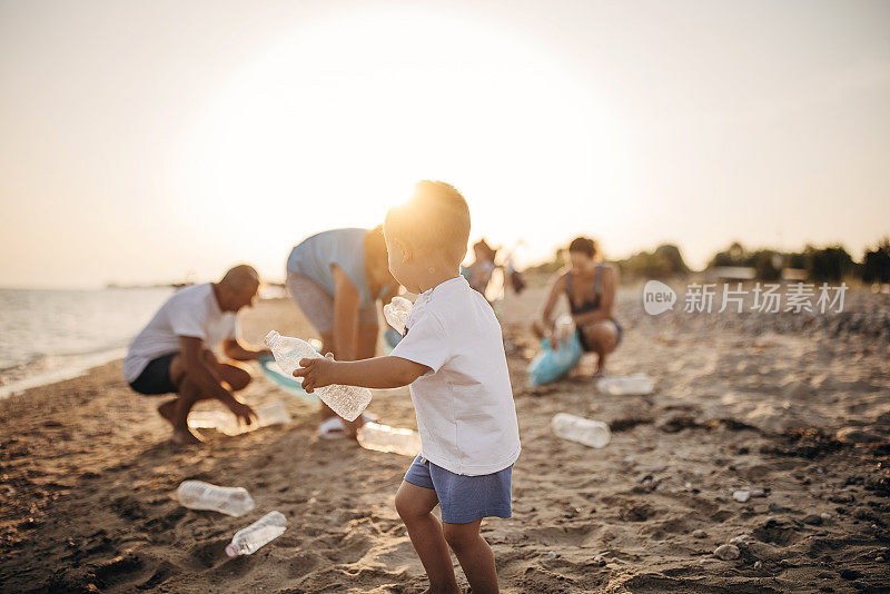 小男孩在沙滩上帮家人捡塑料和垃圾