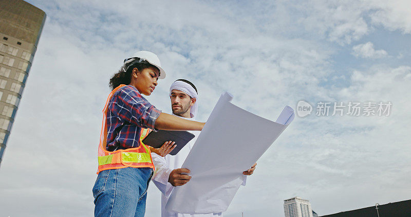 阿拉伯男性工程师与非洲裔美国女性承包商协商，检查和维护建筑的空气、水和电力管道系统。蓝领工人