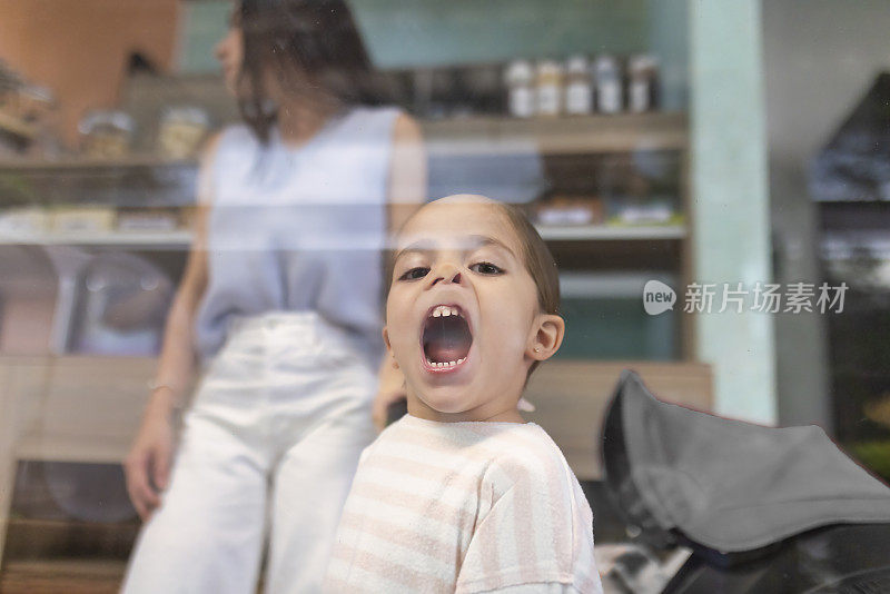 女孩把脸贴在玻璃里做鬼脸