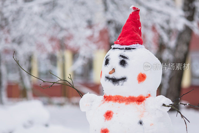 雪人戴着圣诞帽，背景是冬天的雪。寒冷的天气。霜