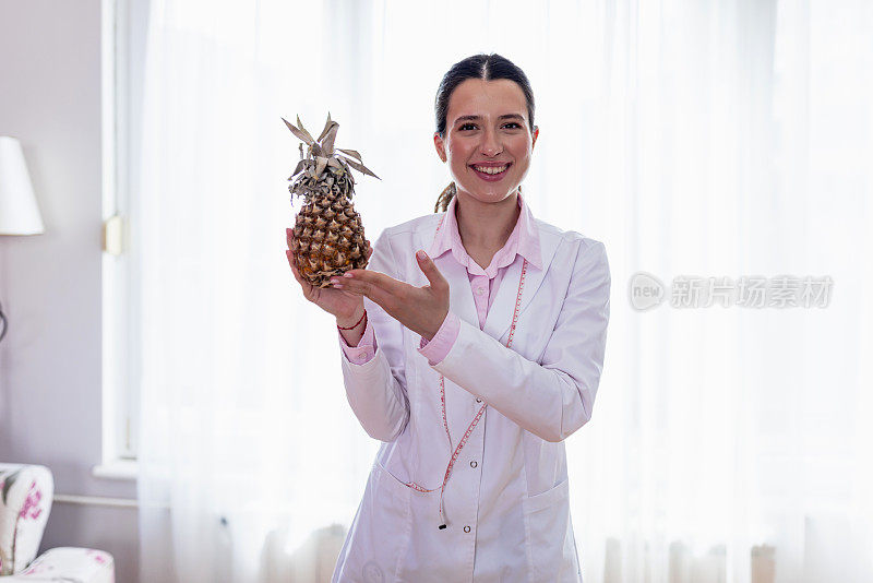 年轻的女性营养学家在白色背景下拿着菠萝