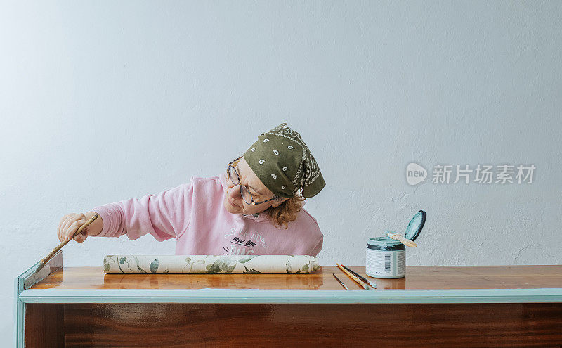 一名成年女子正在给一件古董家具上色。旧事物的新生命概念。古董旧家具件的修复。