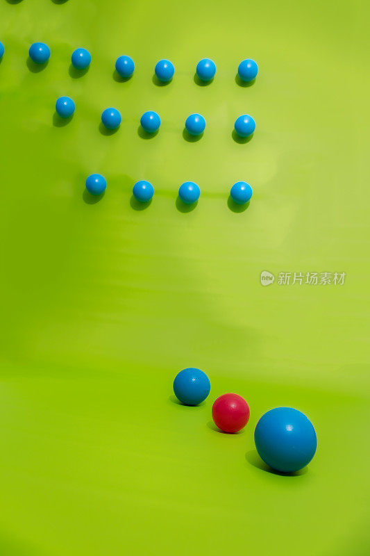 蓝色塑料球衬在绿色背景上，一个红色球