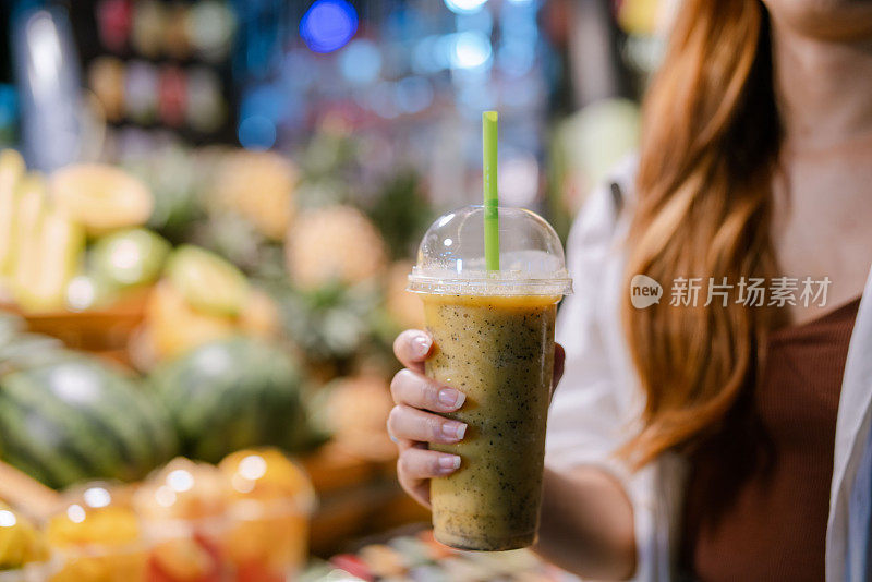 年轻的亚洲女子手里拿着混合饮料。