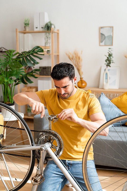 一个年轻人正在家里修自行车。