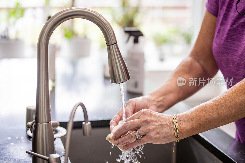 一个女人正在厨房的水槽里洗海绵