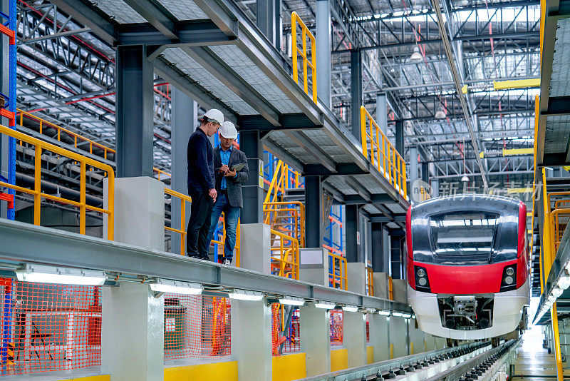 广角镜头专业技术人员和工程师工人站在铁路轨道附近的电气或地铁列车前的工厂工作场所。