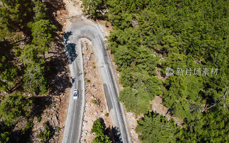 在森林山区的道路上行驶的车辆用无人机拍摄沥青弯道