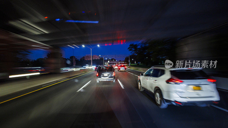 夜间在立交桥下行驶。夜城中灯火通明的高速公路。驱动板