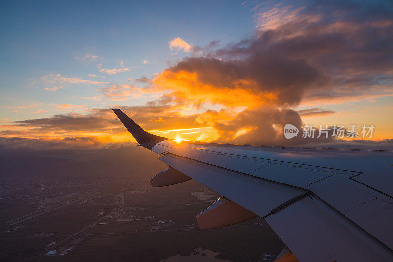 飞机在日落的天空中飞过海水和飞机的机翼。从飞机窗口看到的景象。在空中旅行。