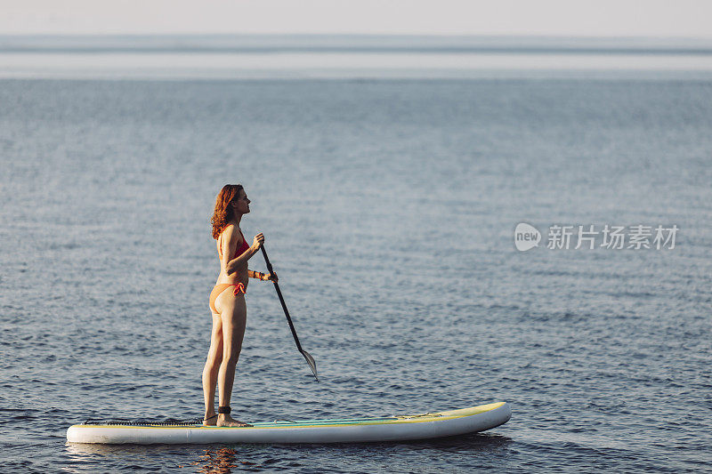 一个女人在湖边玩桨板