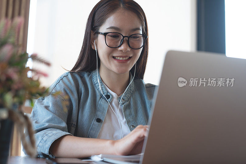 快乐的亚洲休闲商务女性在笔记本电脑上工作，通过在线会议应用程序在咖啡店进行视频会议。学生学习在线课程，电子学习，远程工作，自由职业者的生活方式
